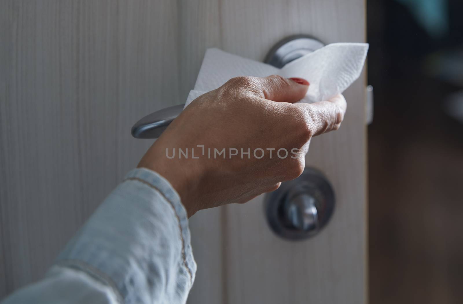 Woman cleaning the door handle with disinfecting wipe by Novic