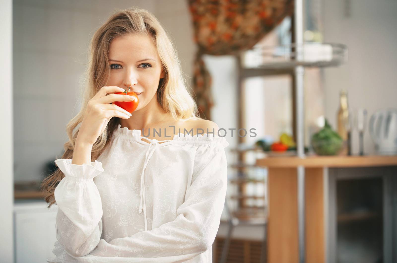 Blond lady with ripe tomato at the kitchen