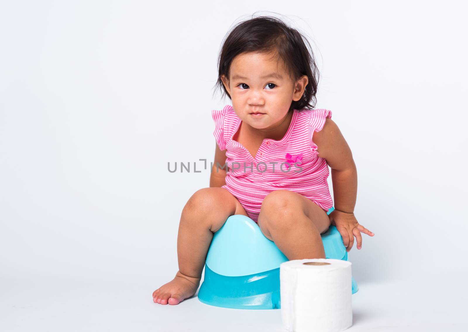 Asian little cute baby child girl education training to sitting on blue chamber pot or potty with toilet paper rolls, studio shot isolated on white background, wc toilet concept