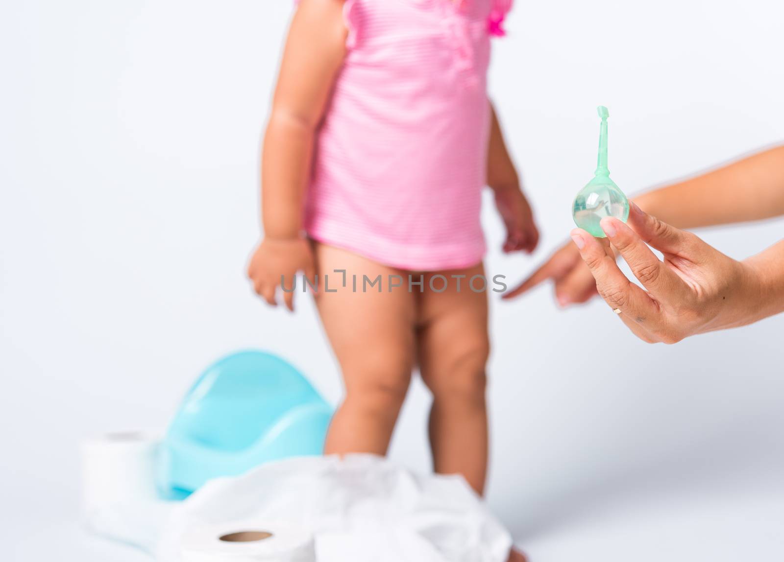 Asian little cute baby child girl training to sitting on blue chamber pot or potty her problem cannot shit and mother use Enema for help, studio shot isolated on white background, wc toilet concept