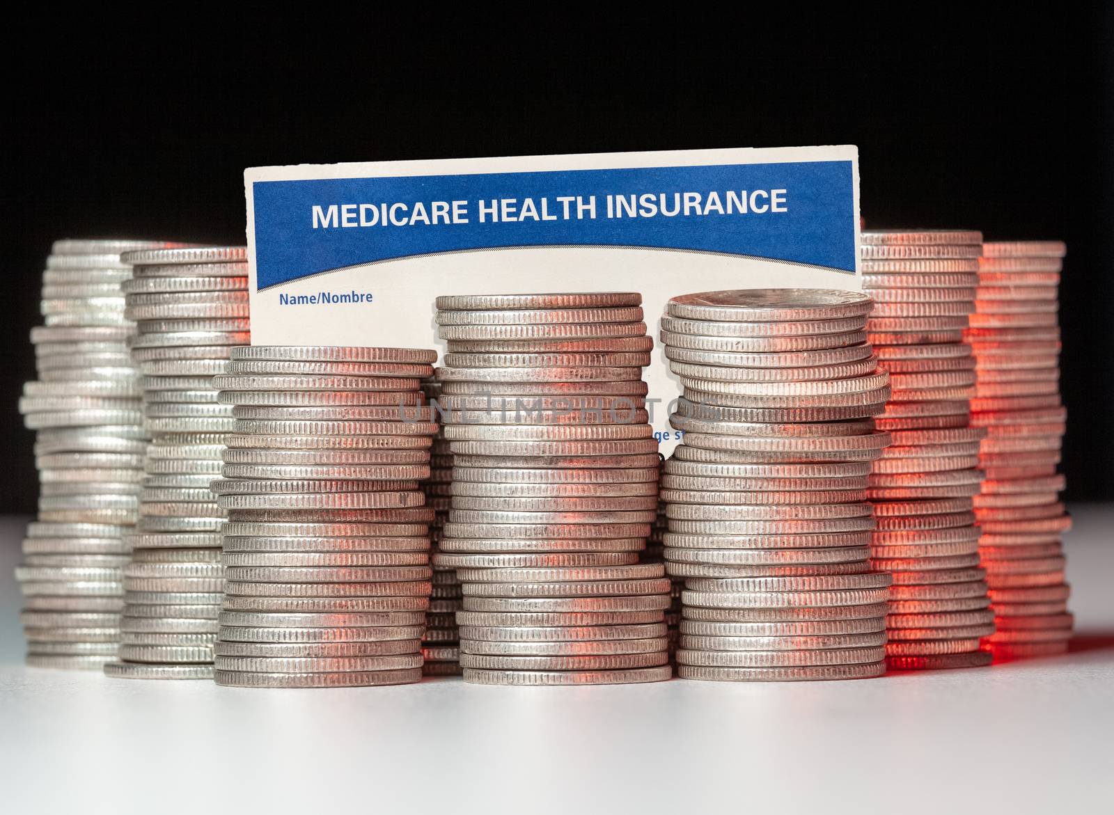 Many stacks of old silver dimes with medicare health insurance card to illustrate budget debt funding issues of the popular program