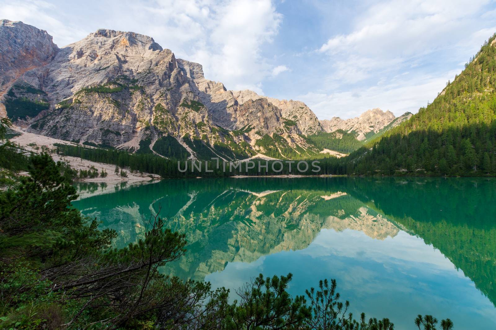 View of Lake Braies under a blue sky with white clouds, in the background the Seekofel or Croda del Becco