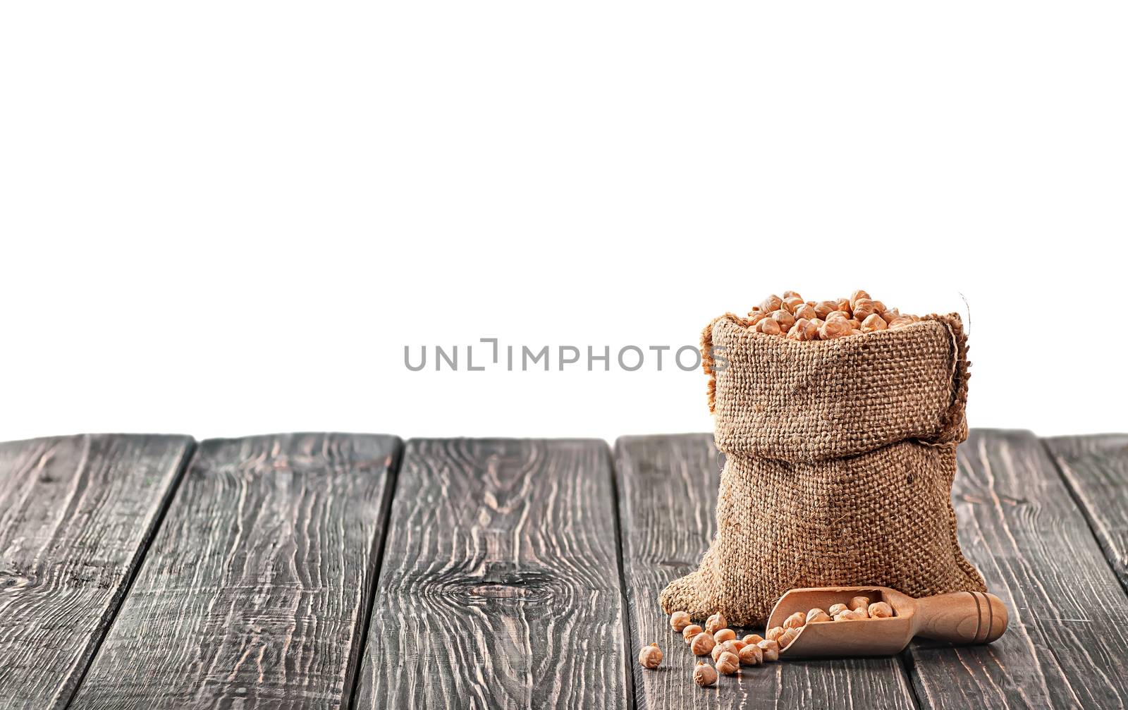 Bag with chickpeas and scoop near on table isolated on white background