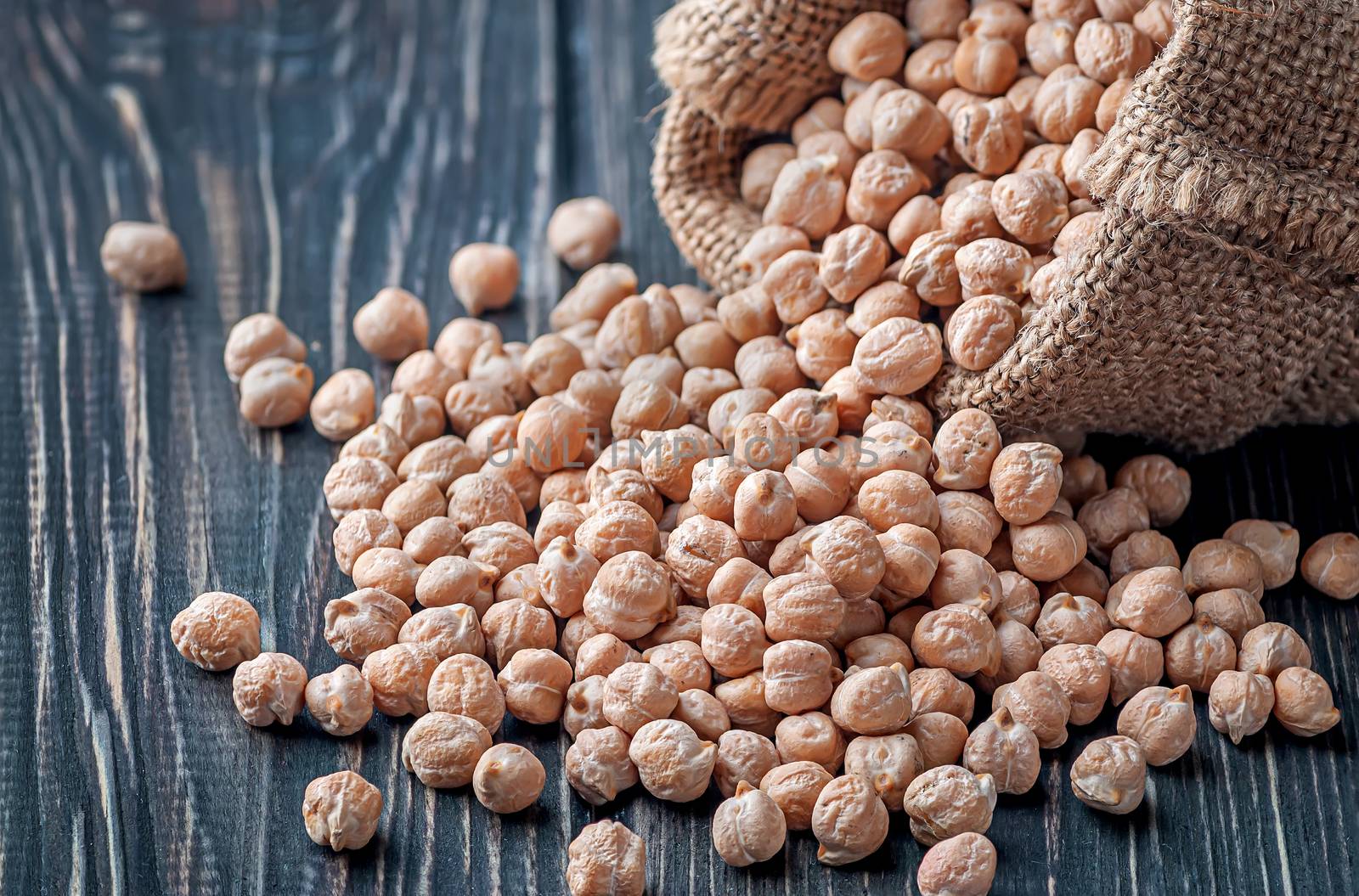 Chickpea spill out of the bag closeup on wooden background