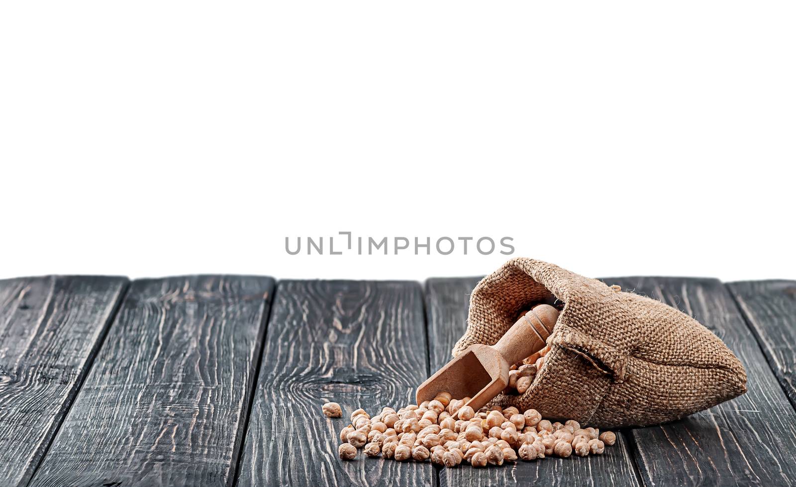 Chickpea spill out of the bag and wooden scoop on table isolated on white background