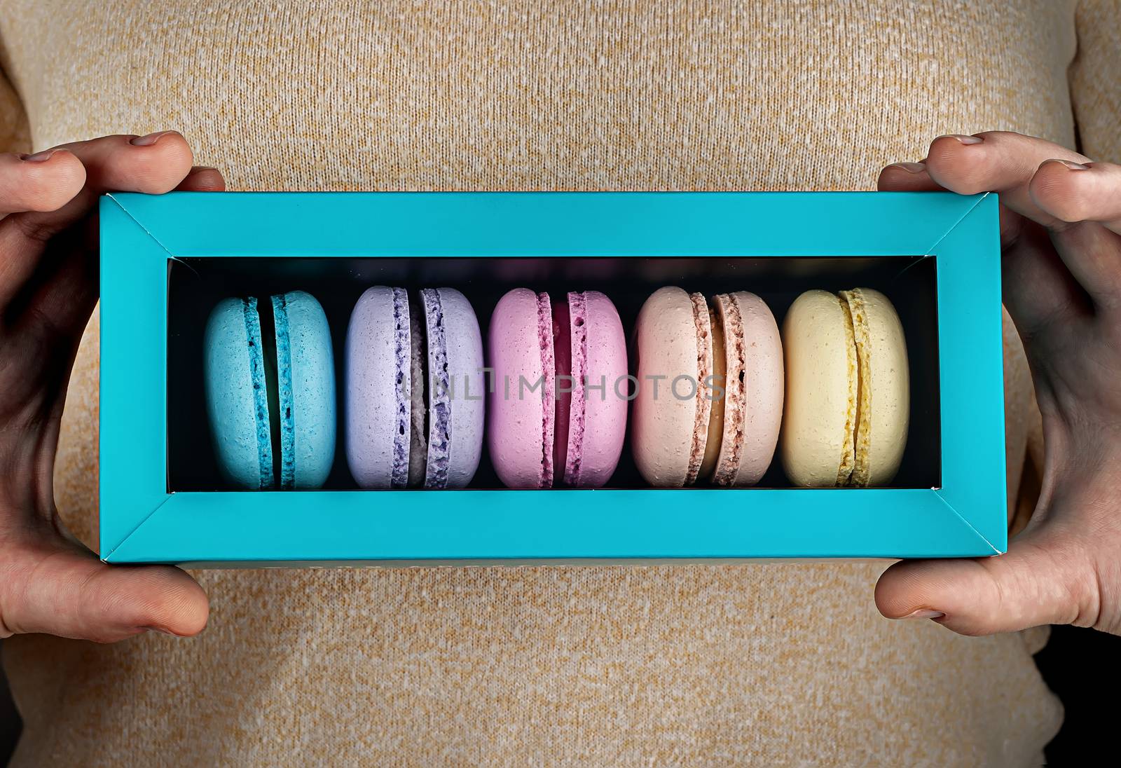 Closeup macaroons in gift box in hands by Cipariss