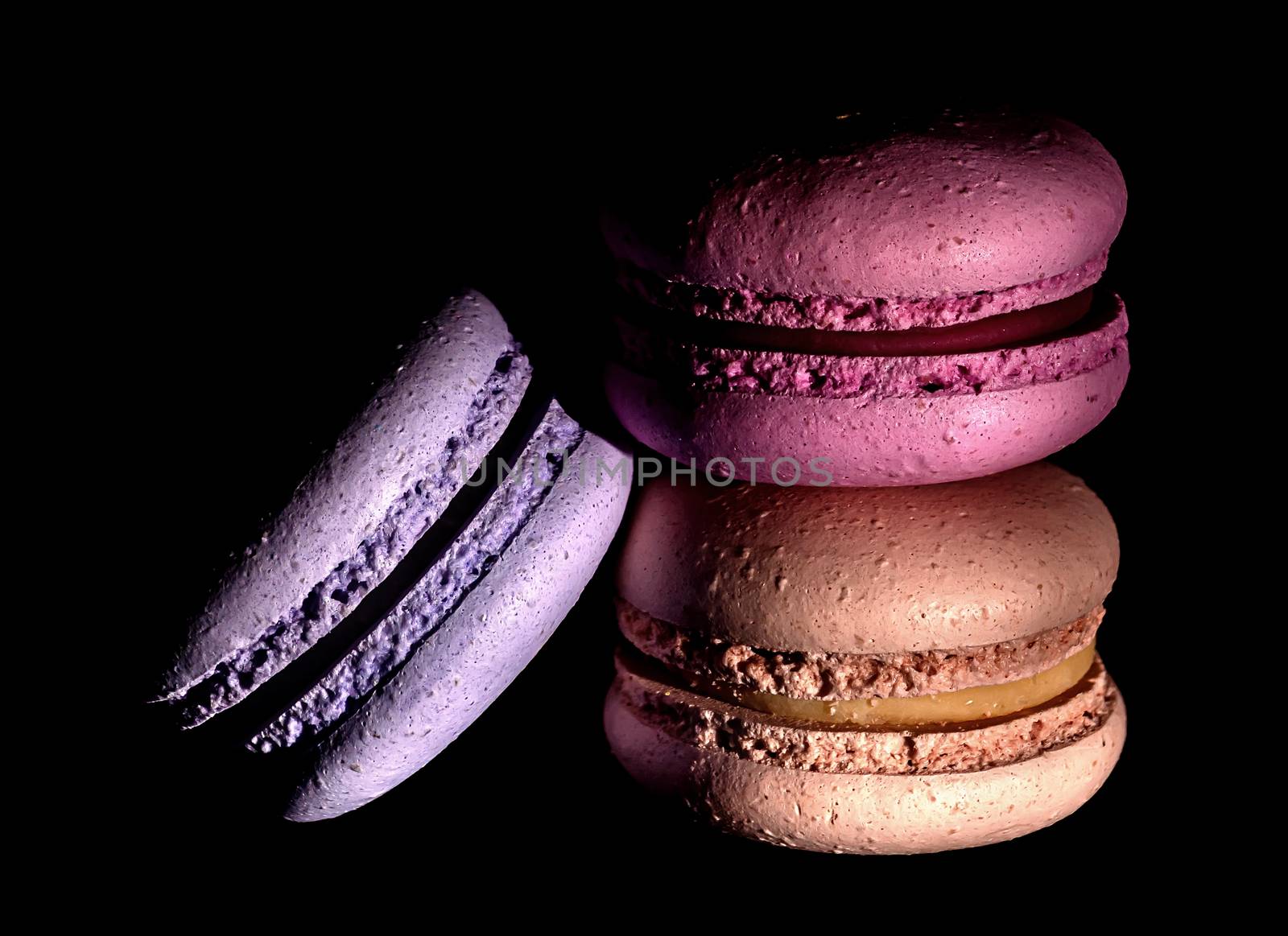 Heap of colorful macaroons on black background darkened