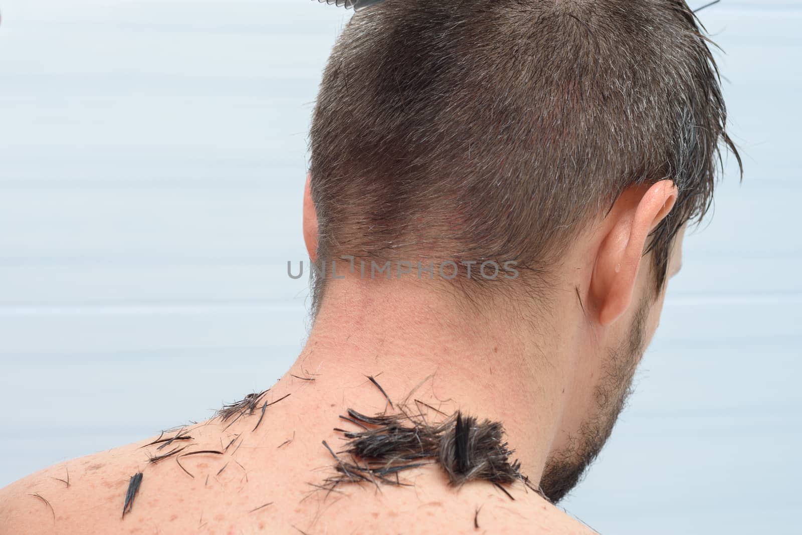The back of the head of a man whose hair is cut at home in the bathroom