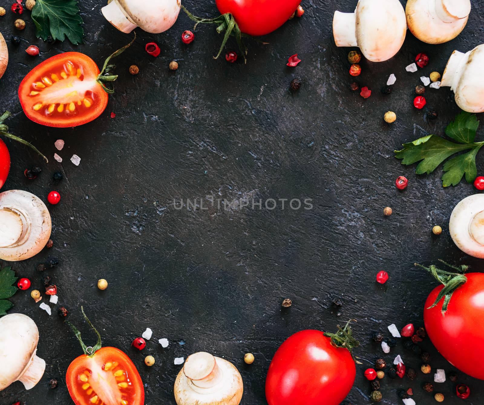 Food ingredients on black background, copy space in center. Mini champignons, cherry tomatoes, herbs and spices top view or flat lay