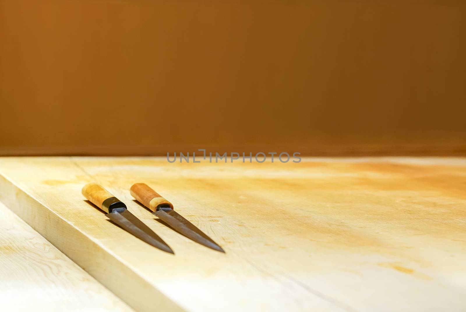 2 sushi knives on a wooden counter. Enjoy Omakase experience at Japanese Sushi Restaurant.