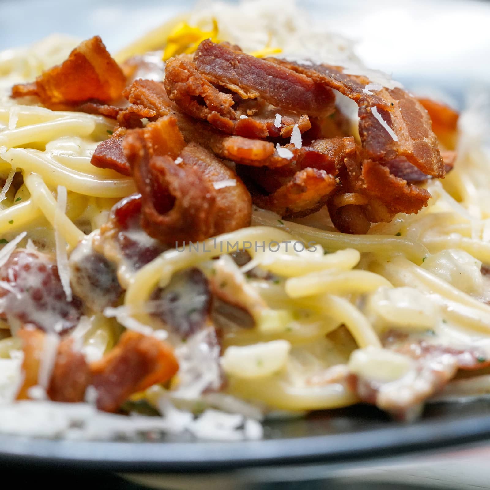 Close up Spaghetti, a delicious pasta served on black plate. Carbonara made with egg, hard cheese, guanciale, bacon and black pepper. Food Background.