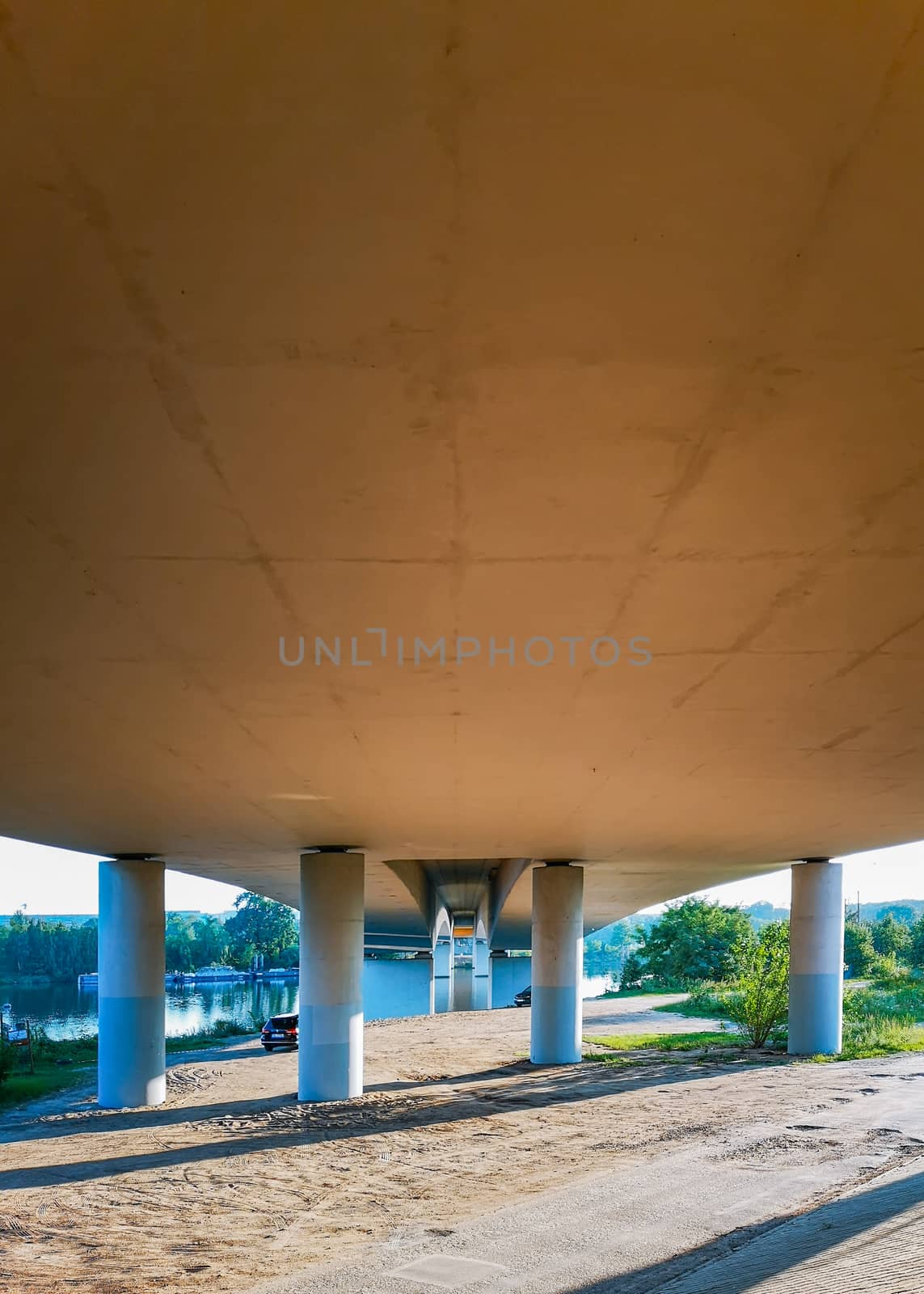 Concrete pillars under bridge on beach near river by Wierzchu