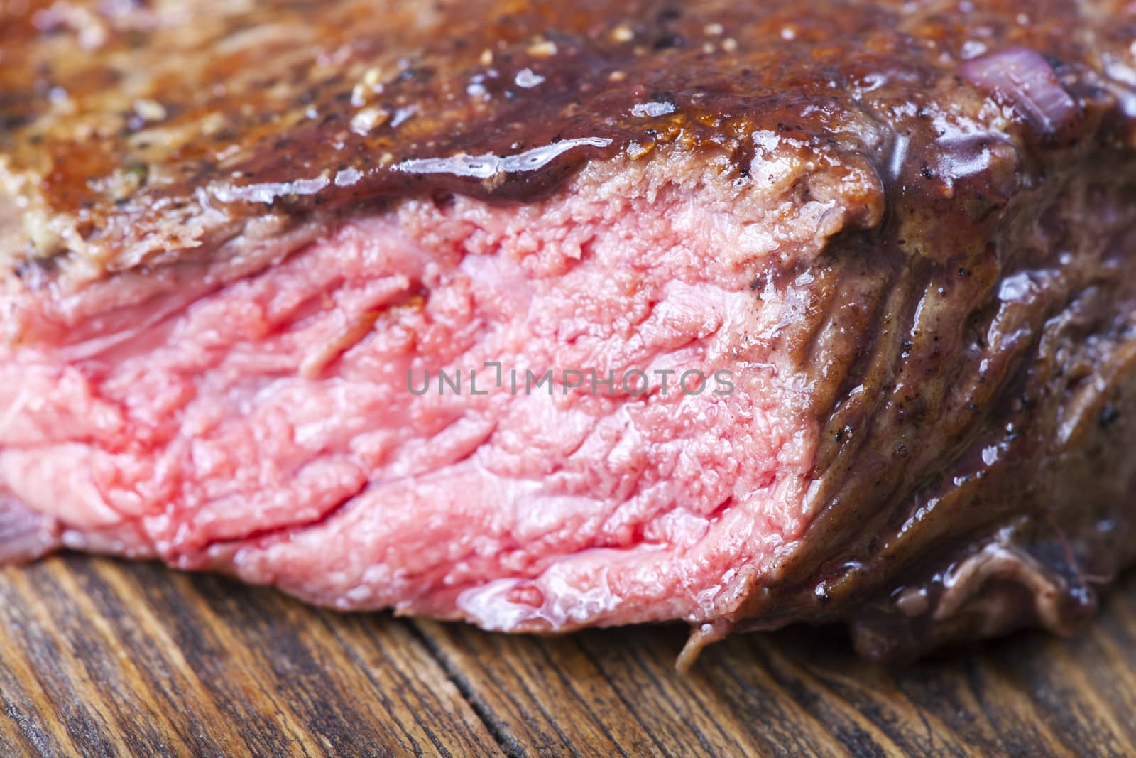 slices of a steak on wood with rosemary