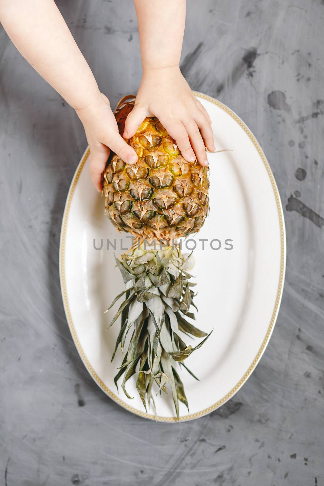 White Plate with Ripe Whole Pineapple on Grey Concrete Background