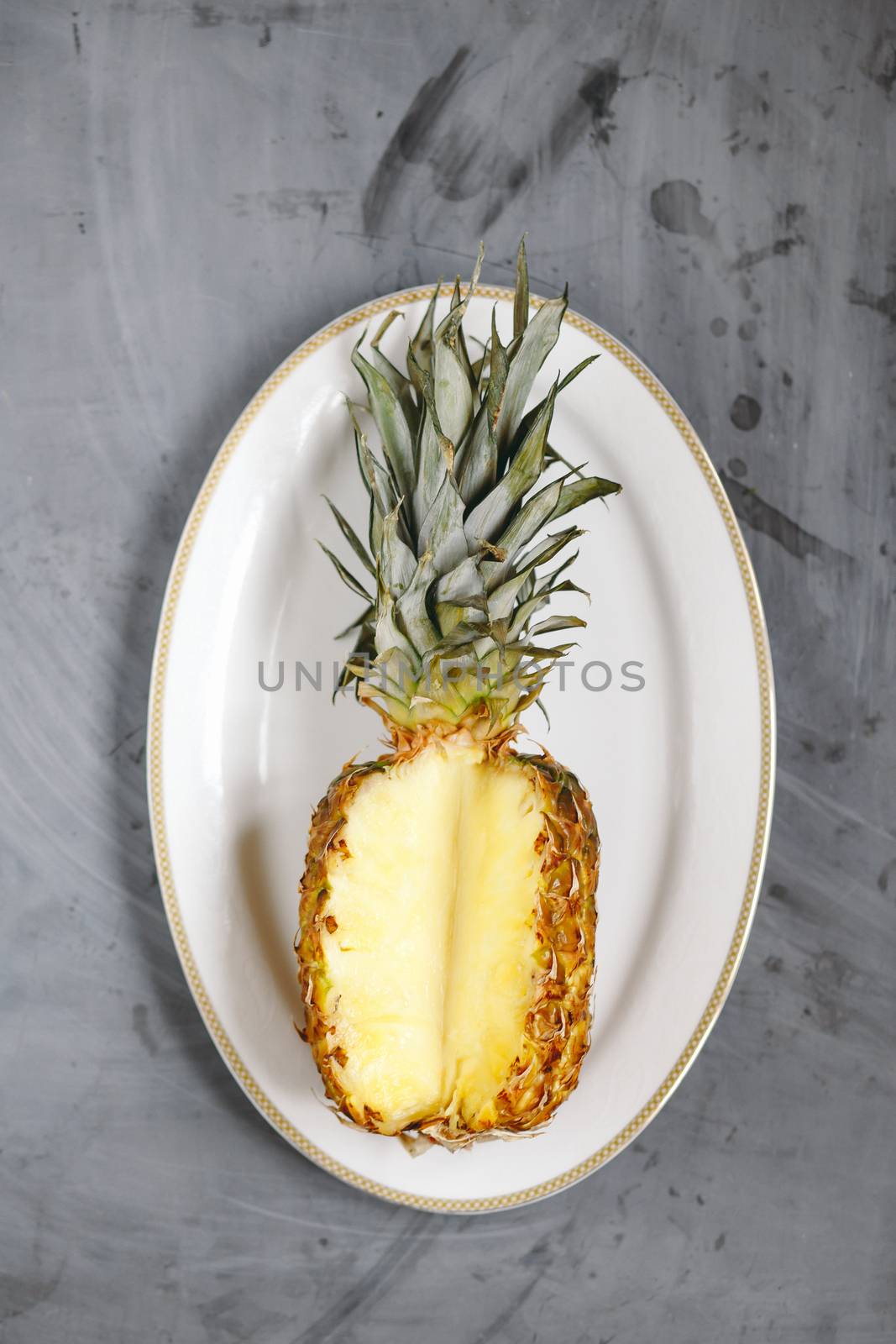 White Plate with Ripe Sliced Pineapple on Grey Concrete Background