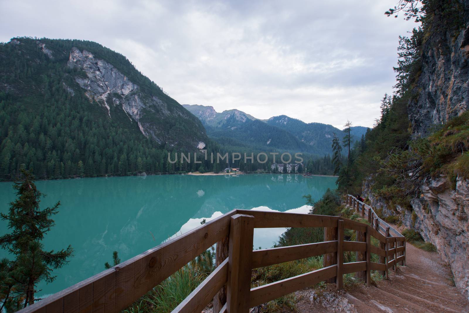 Dirt path to staircase runs along the Braies Lake under a cloudy sky, Trentino Alto Adige