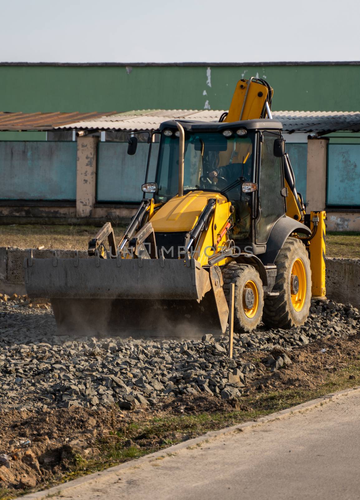 Yellow wheel loader Excavator machine working at construction site with a sand and gravel. Preparing of the fundament for a asphalting. Road construction site. Building of a parking