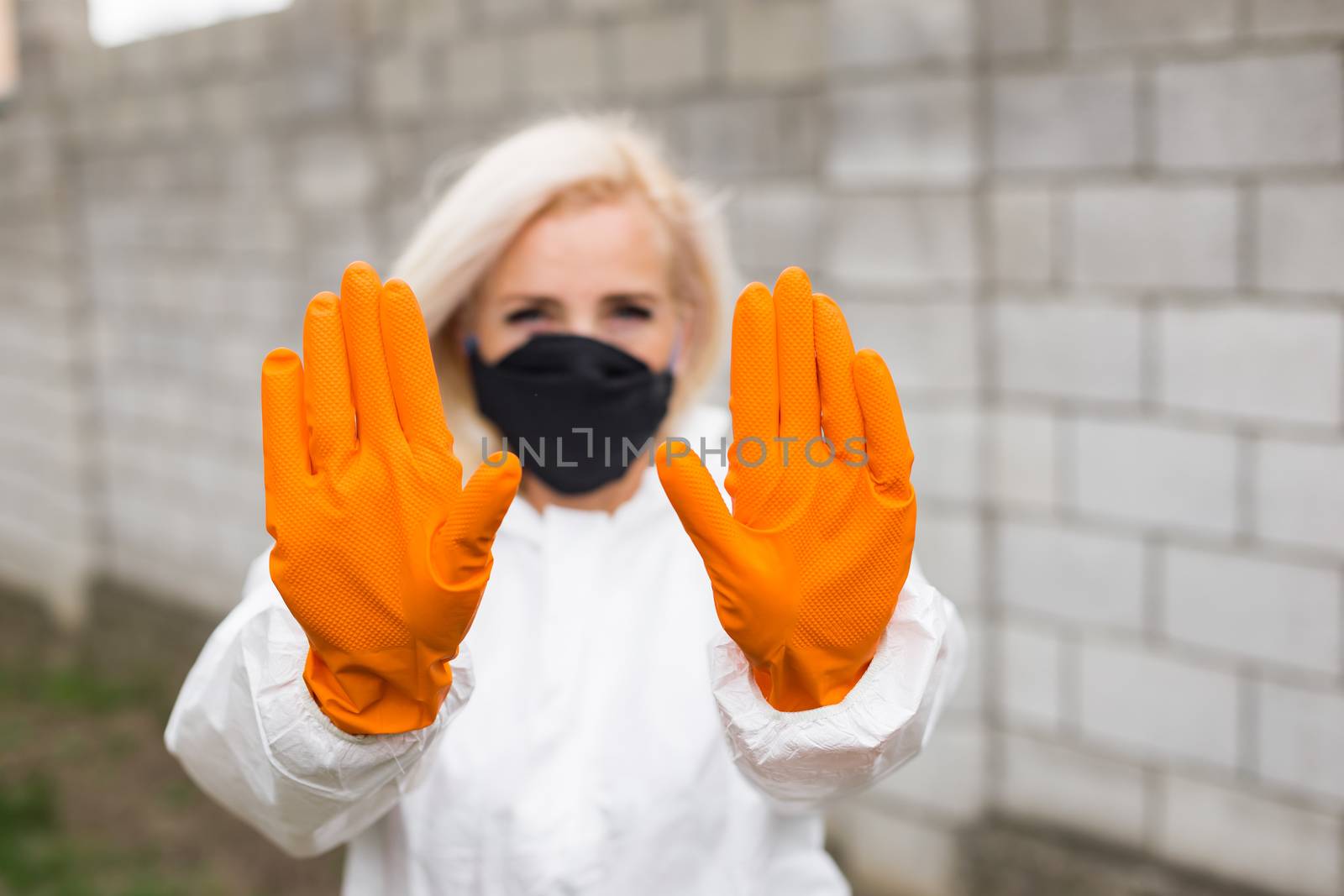 Woman in black mask, white protective suit and gloves making sigh stop by Angel_a