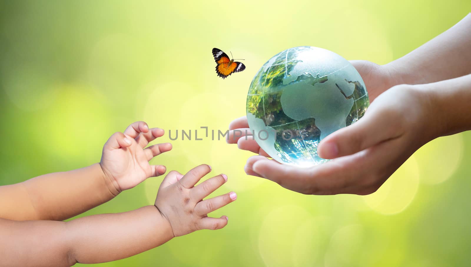 Adults are sending the world to babies. Concept day earth Save the world save environment The world is in the grass of the green bokeh background