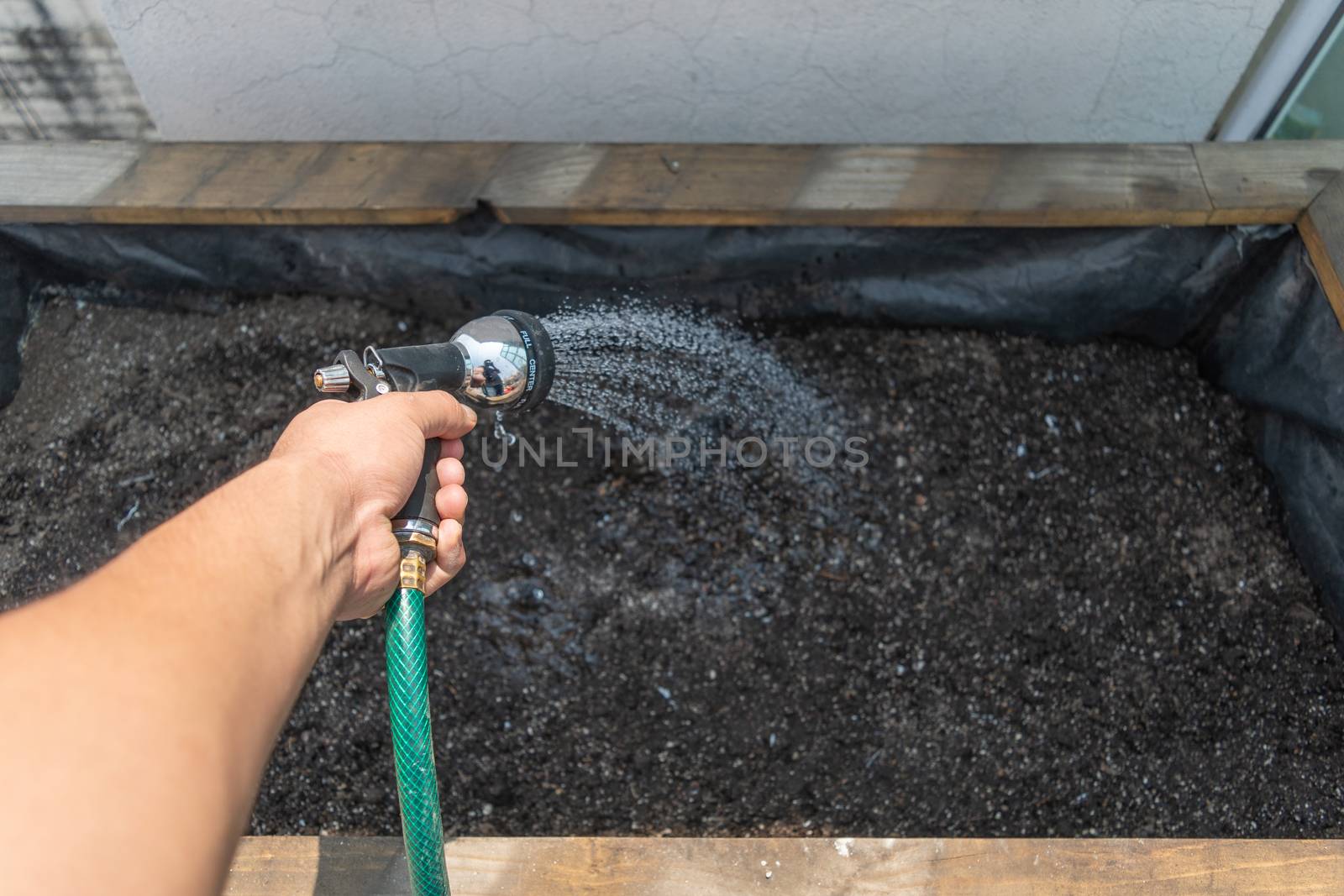 Hand carrying a hose to irrigate a grow bed