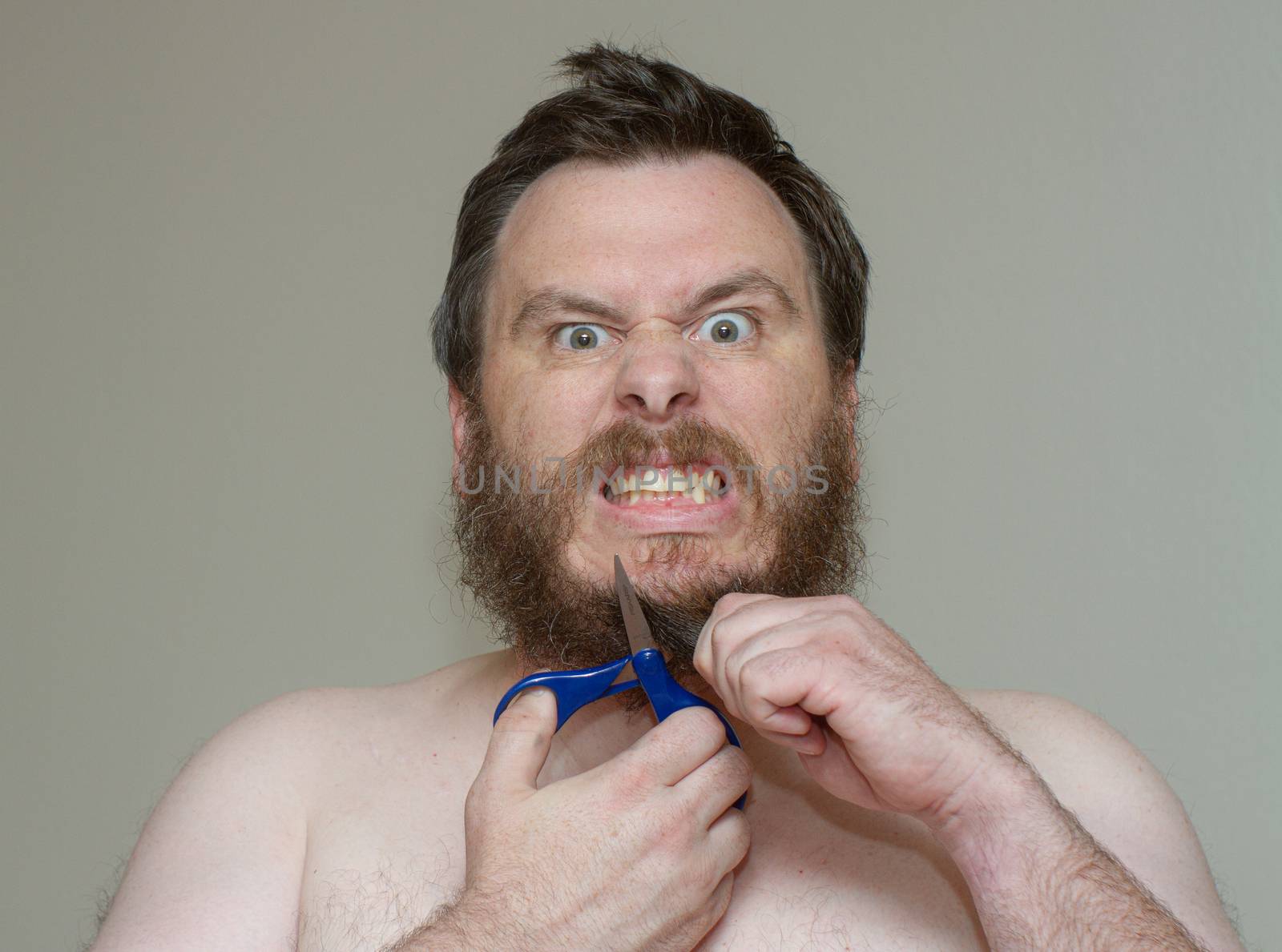 with a stressed look on his face a man tries to cut his beard