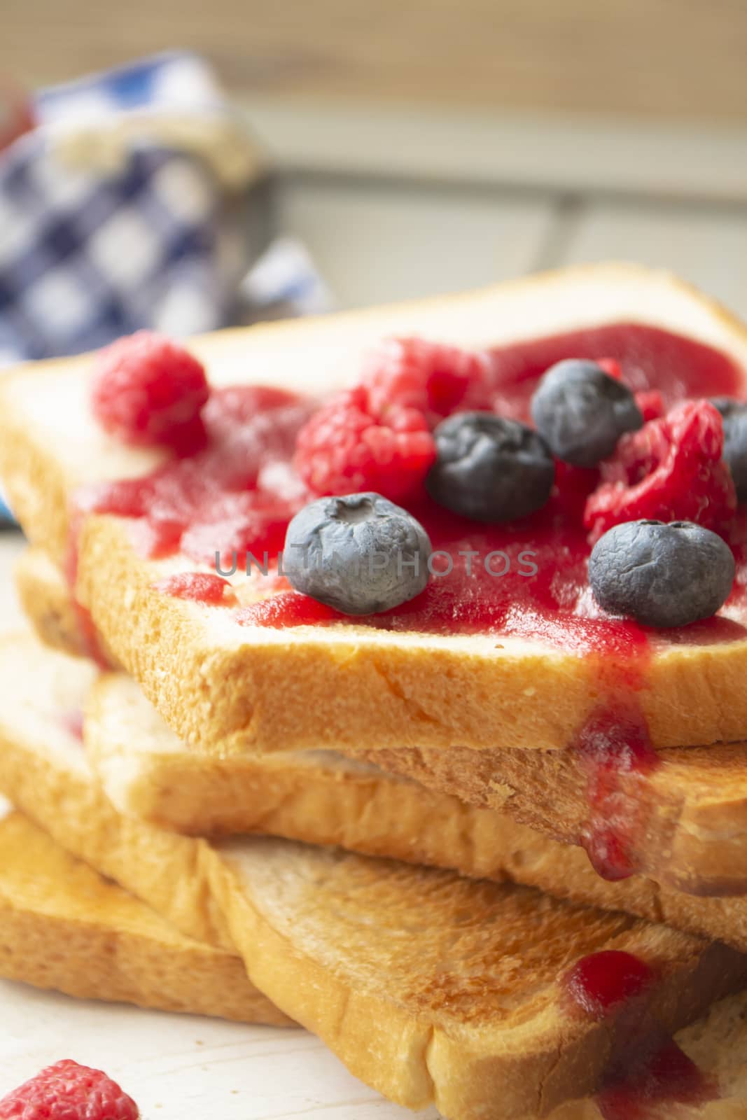 Toasted bread with sweet raspberry and blueberry jam for breakfast, vertical image