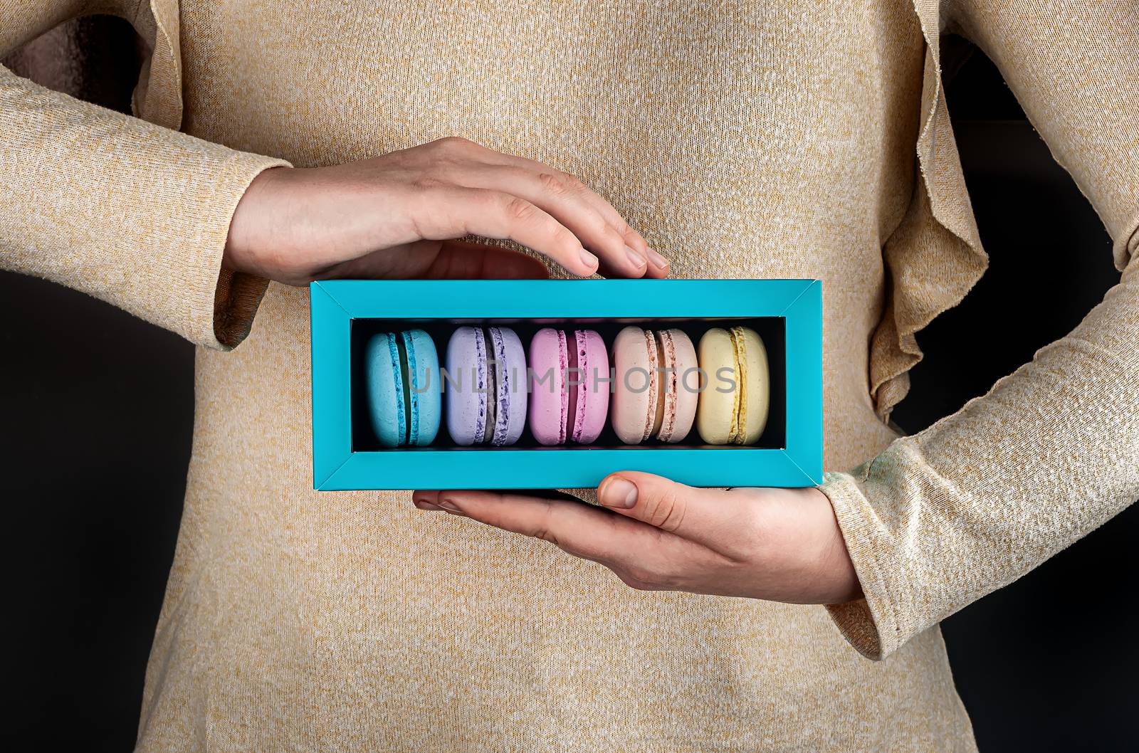 Female hands hold macaroons in box by Cipariss