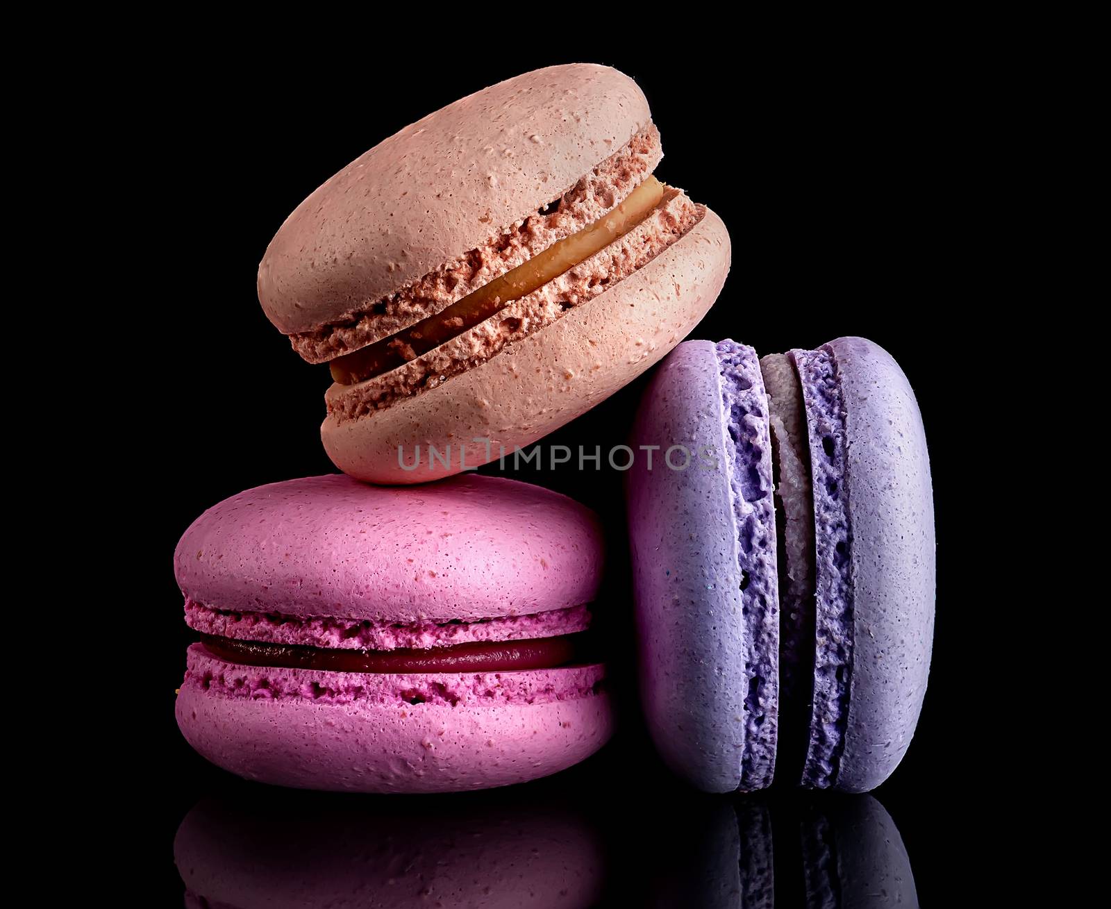 Heap of colorful macaroons on black background
