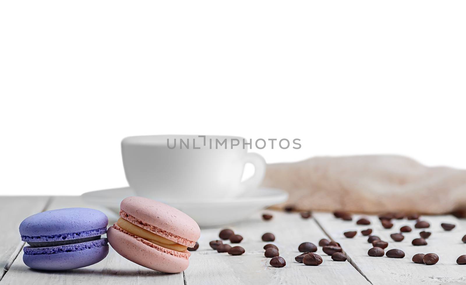 Two macaroons with a cup, coffee beans and towel isolated on white background