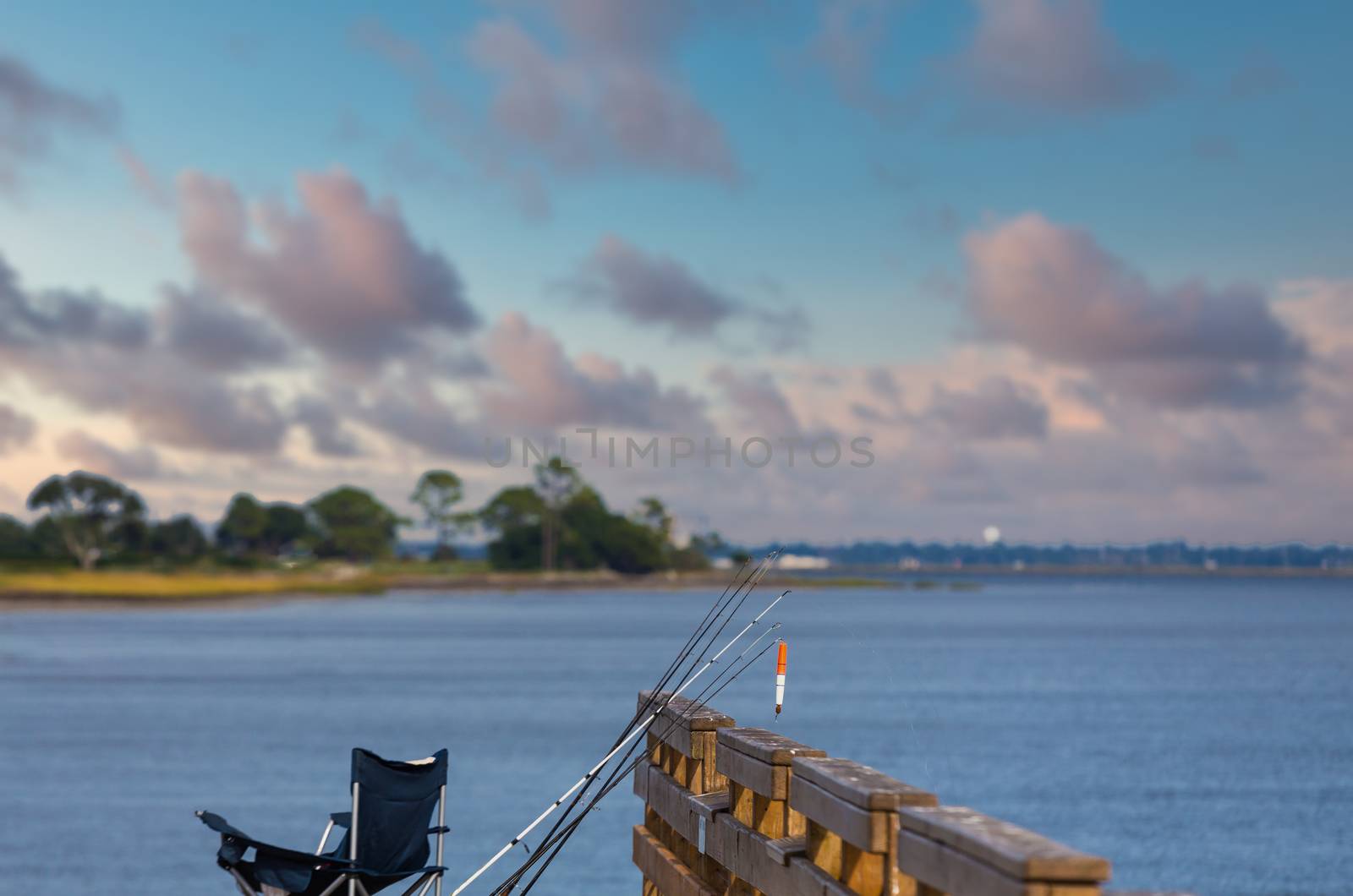 Fishing poles leaning against a pier over a calm sea