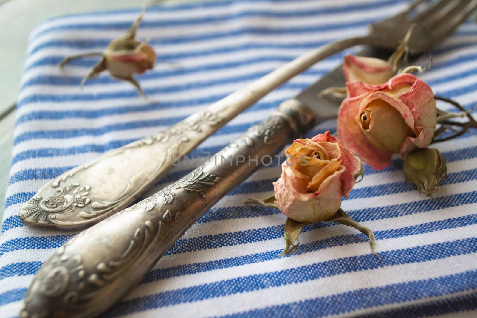 Vintage table setting with floral decorations, blue napkins, dry roses