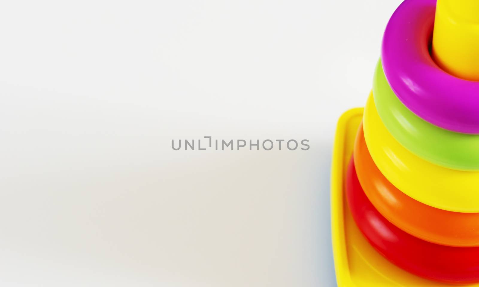 Plastic rings of various colors are stacked in a yellow plastic tower. by rarrarorro