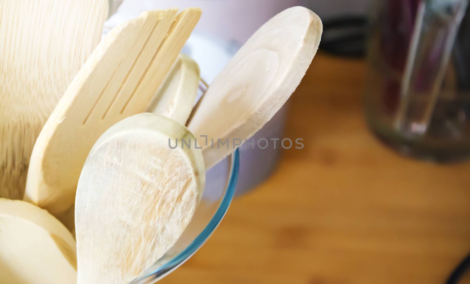 Close-up view of a group of wooden kitchen utensils inside a glass container. Cooking with traditional utensils