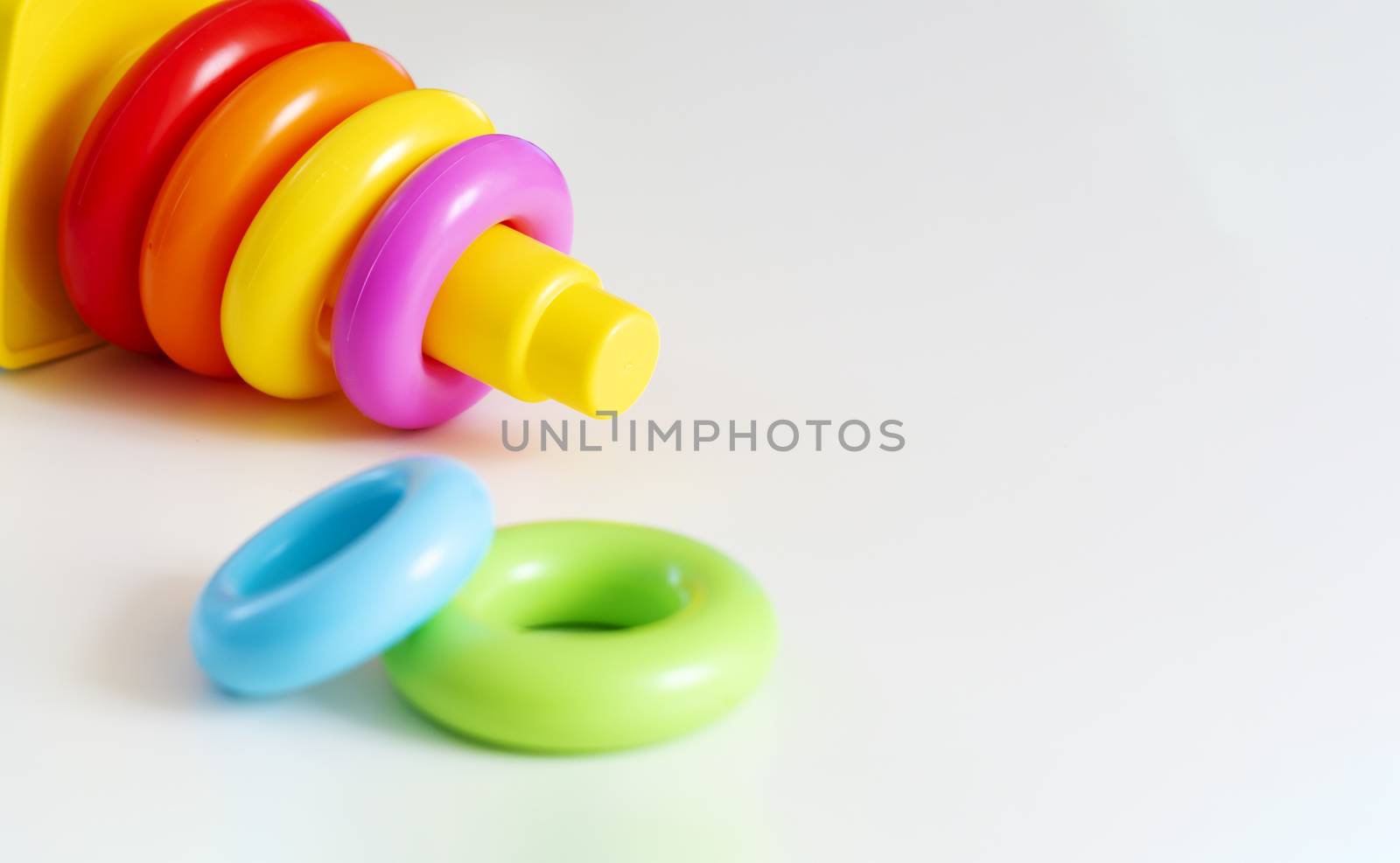 Plastic rings of various colors are stacked in a yellow plastic tower. by rarrarorro
