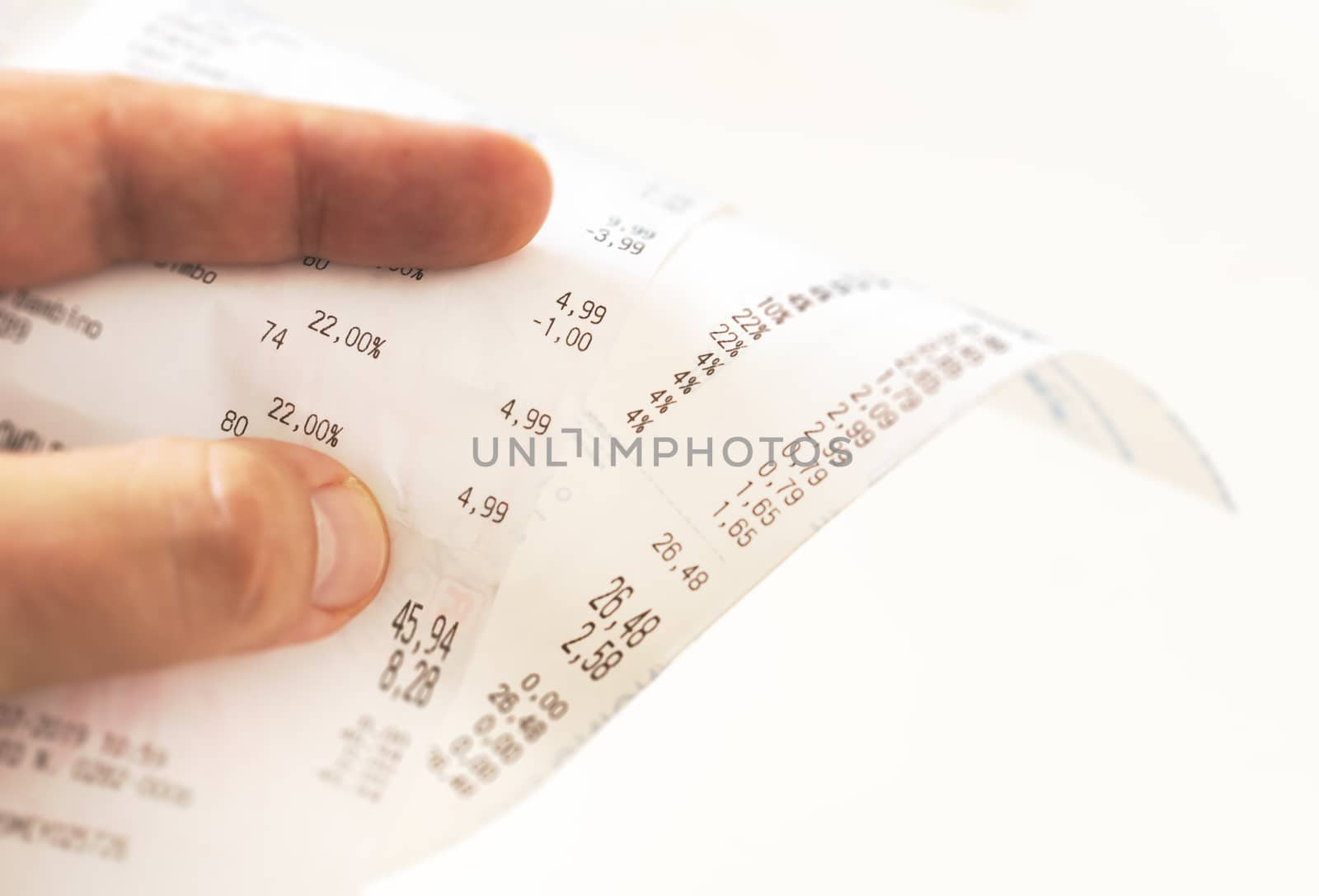 human fingers holding a paper receipt with the bill of charges and checking the total amount. Domestic finance. Tax receipt on a roll of thermal paper