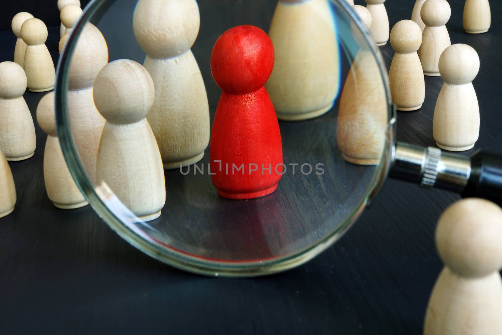Recruitment Sourcing and strategies concept. Magnifying glass and red figurine. by designer491