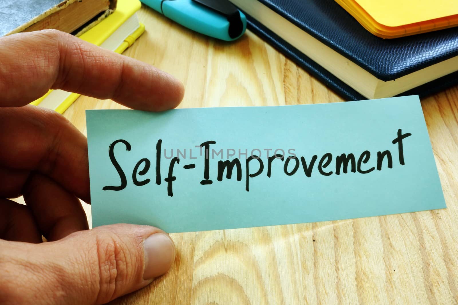 Hand holds piece of paper with sign Self improvement. by designer491