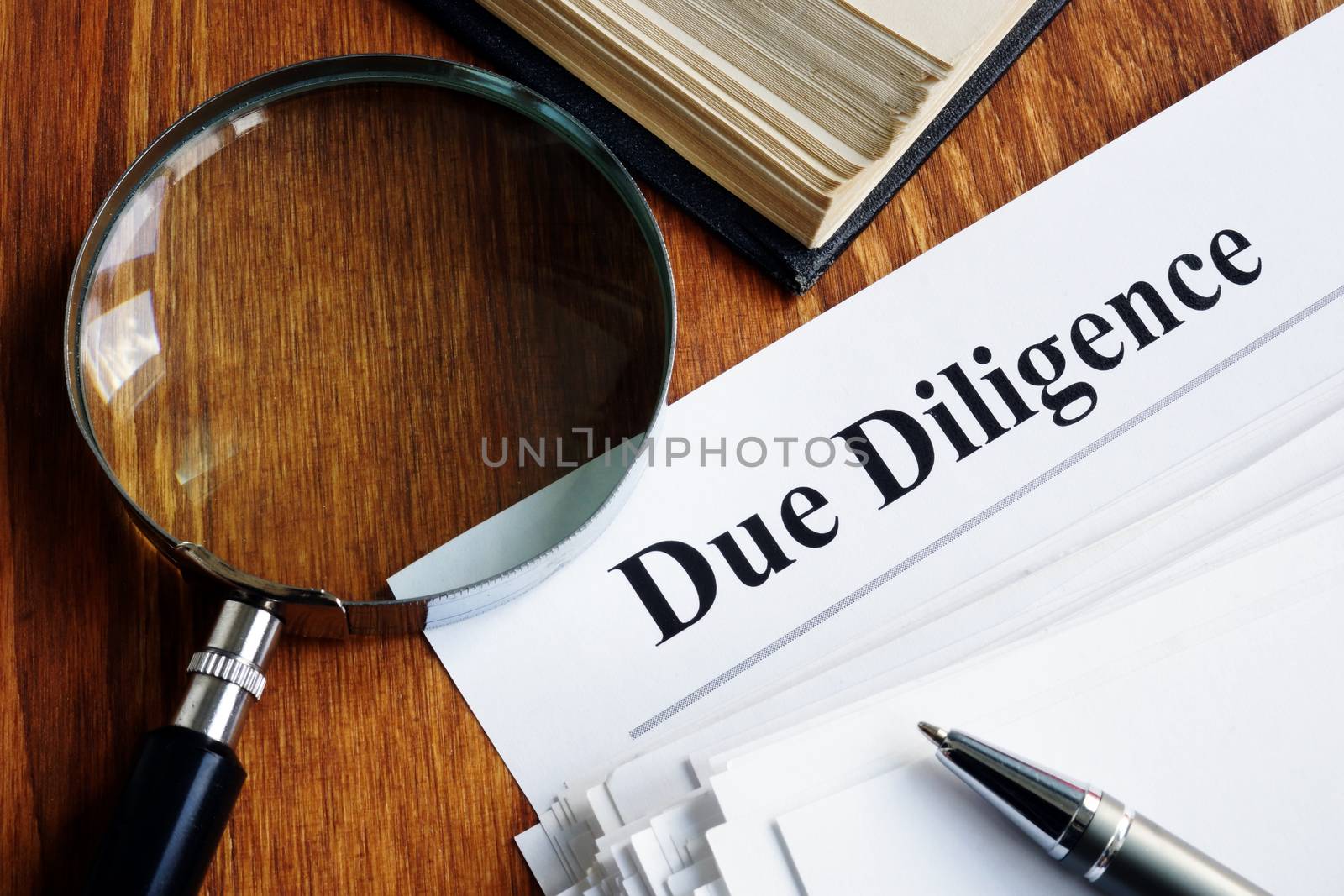Due Diligence concept. Stack of documents and magnifying glass. by designer491