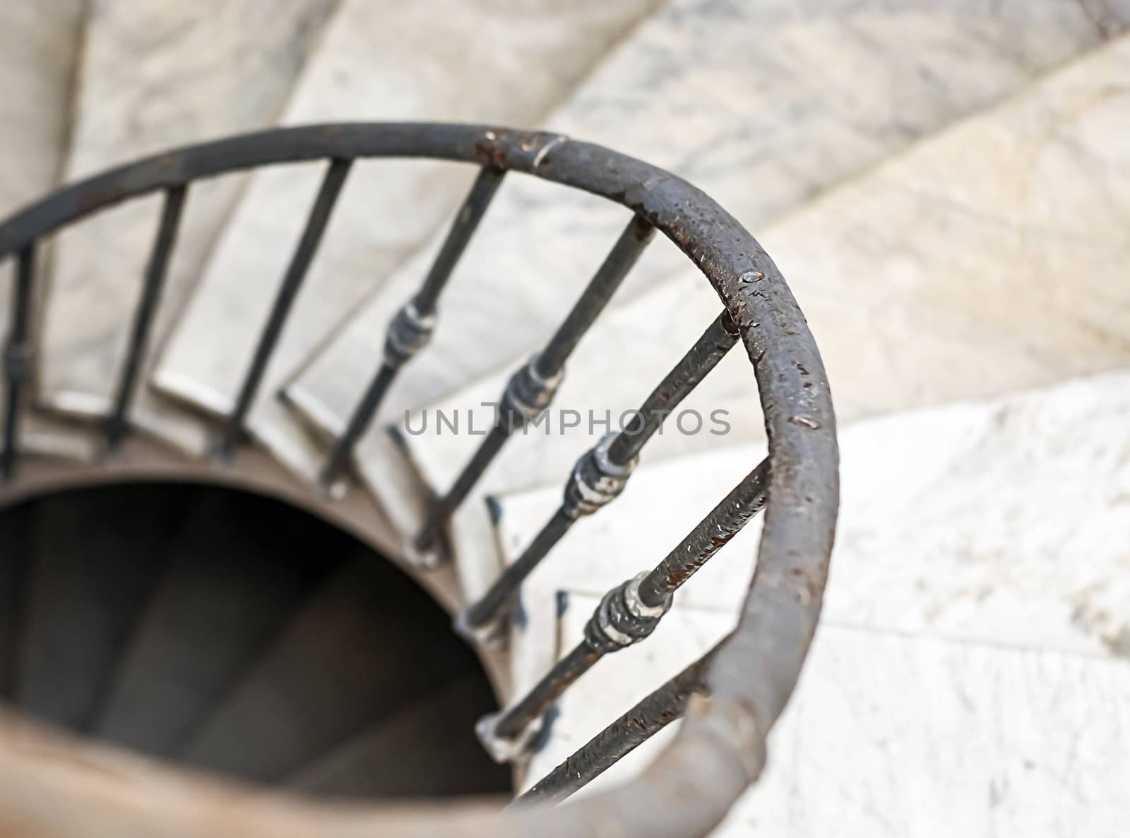 ancient spiral staircase with marble steps and wrought iron handrail. Architecture and circular shape