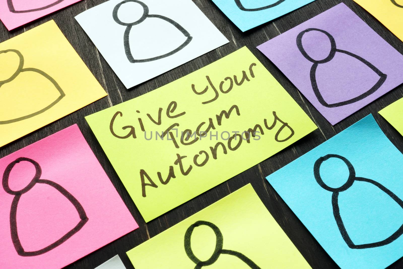 Give Your Team Autonomy sign and drawn smiles faces. by designer491