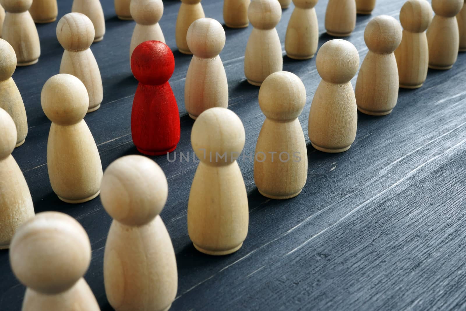 Unique and different concept. Crowd of wooden figures and red one.