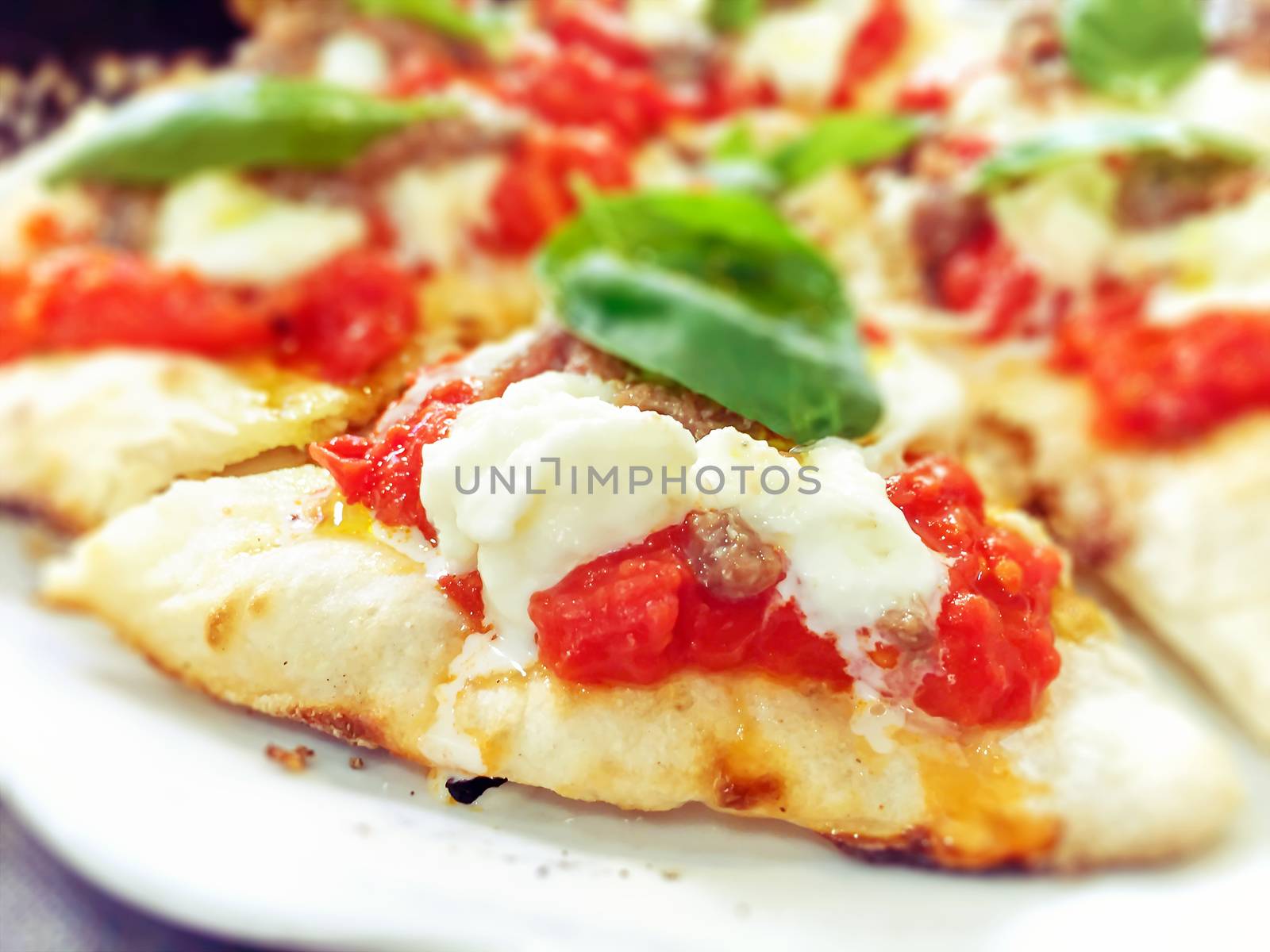 close-up view of a margherita pizza with fresh tomatoes, mozzarella cheese and basil leaves. Typical Neapolitan and Italian recipe