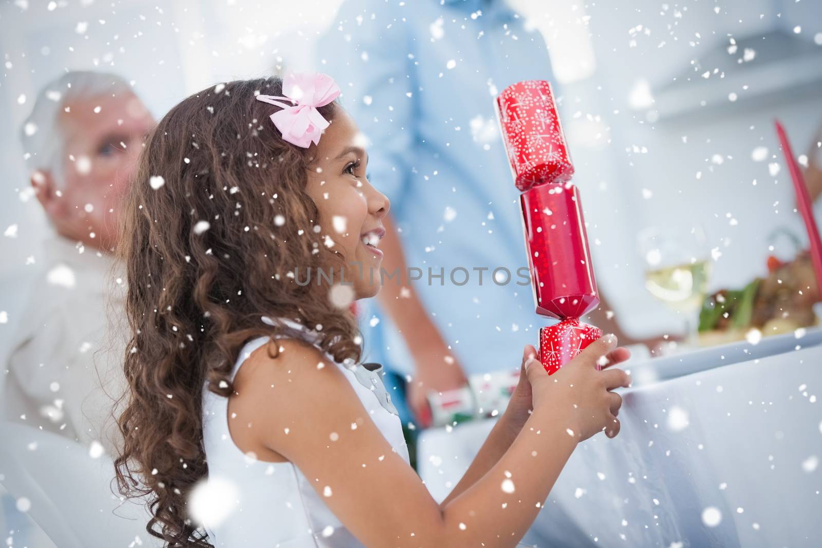 Composite image of Cute little girl holding crackers against snow falling