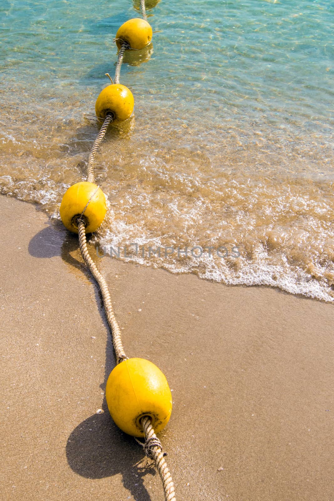 Floating buoy and rope dividing the area on the beach