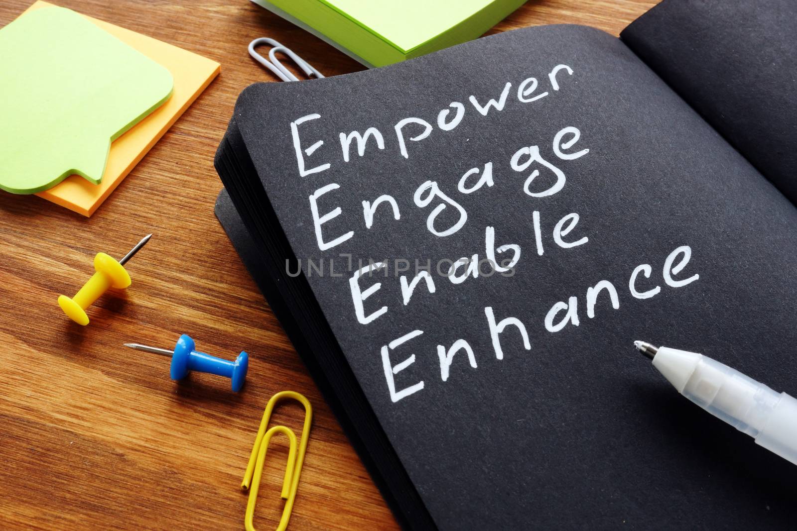 Empower engage enable enhance words written in the notepad. by designer491