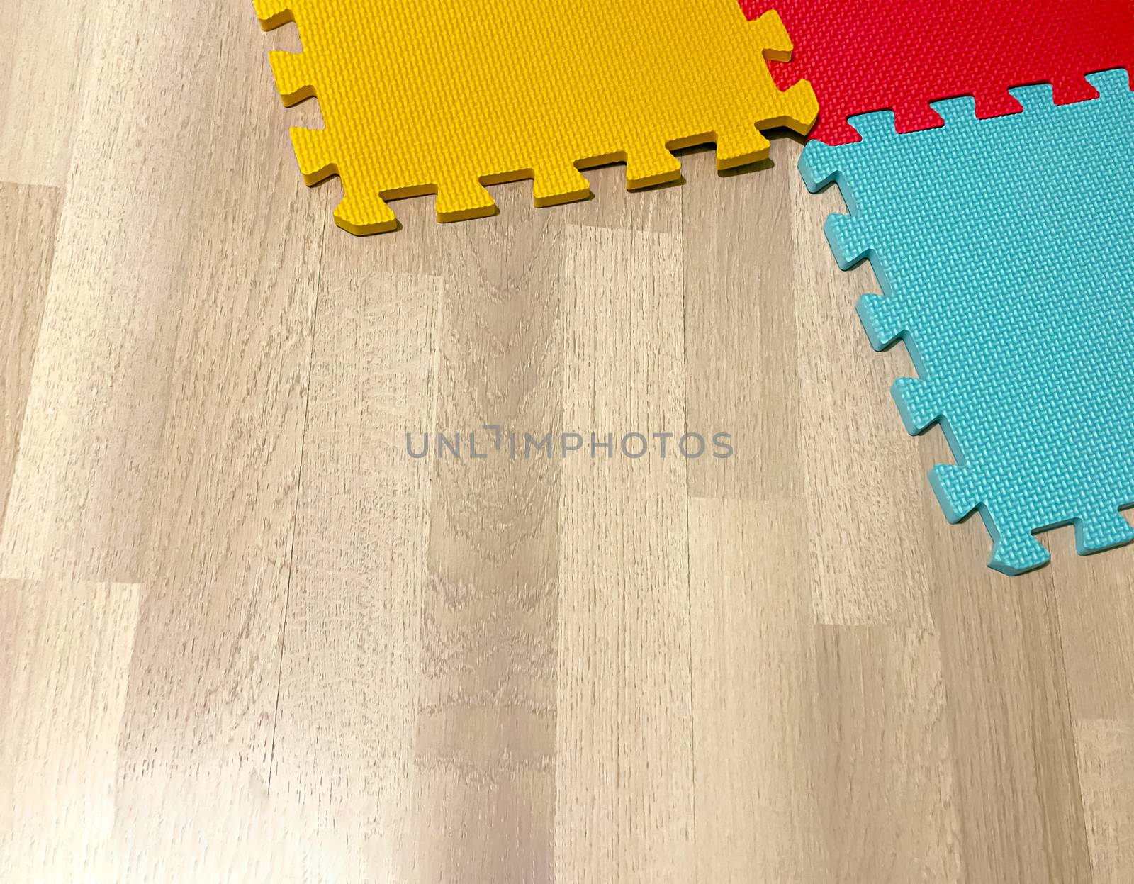 Soft rubber mat composed of colored blocks intersected with each other on a wooden floor. Suitable for children to play or for yoga exercises. Interior shot
