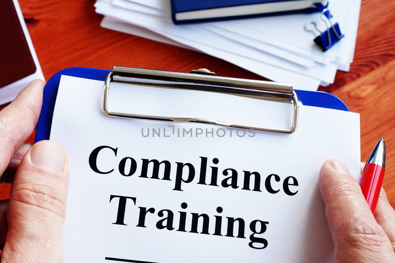Man is holding compliance training report papers. by designer491