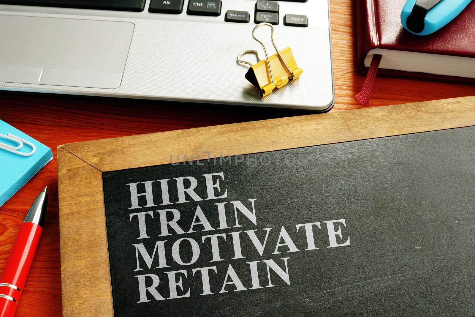 Staff hire, train, motivate and retain written on the blackboard. by designer491
