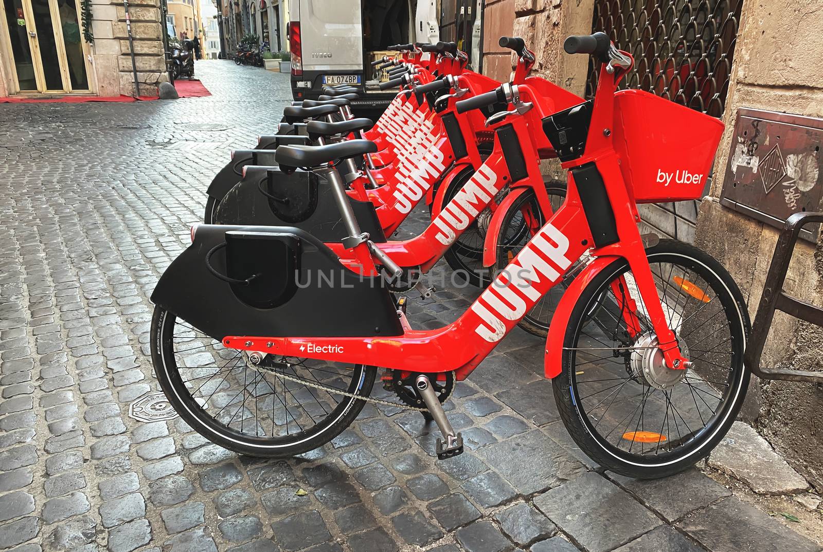 Rome, Italy, January 8, 2020: a group of red electric bicycles of the Uber Jump bike-sharing service park in a street in the center of Rome. Concept of sustainable mobility and eco-sustainable
