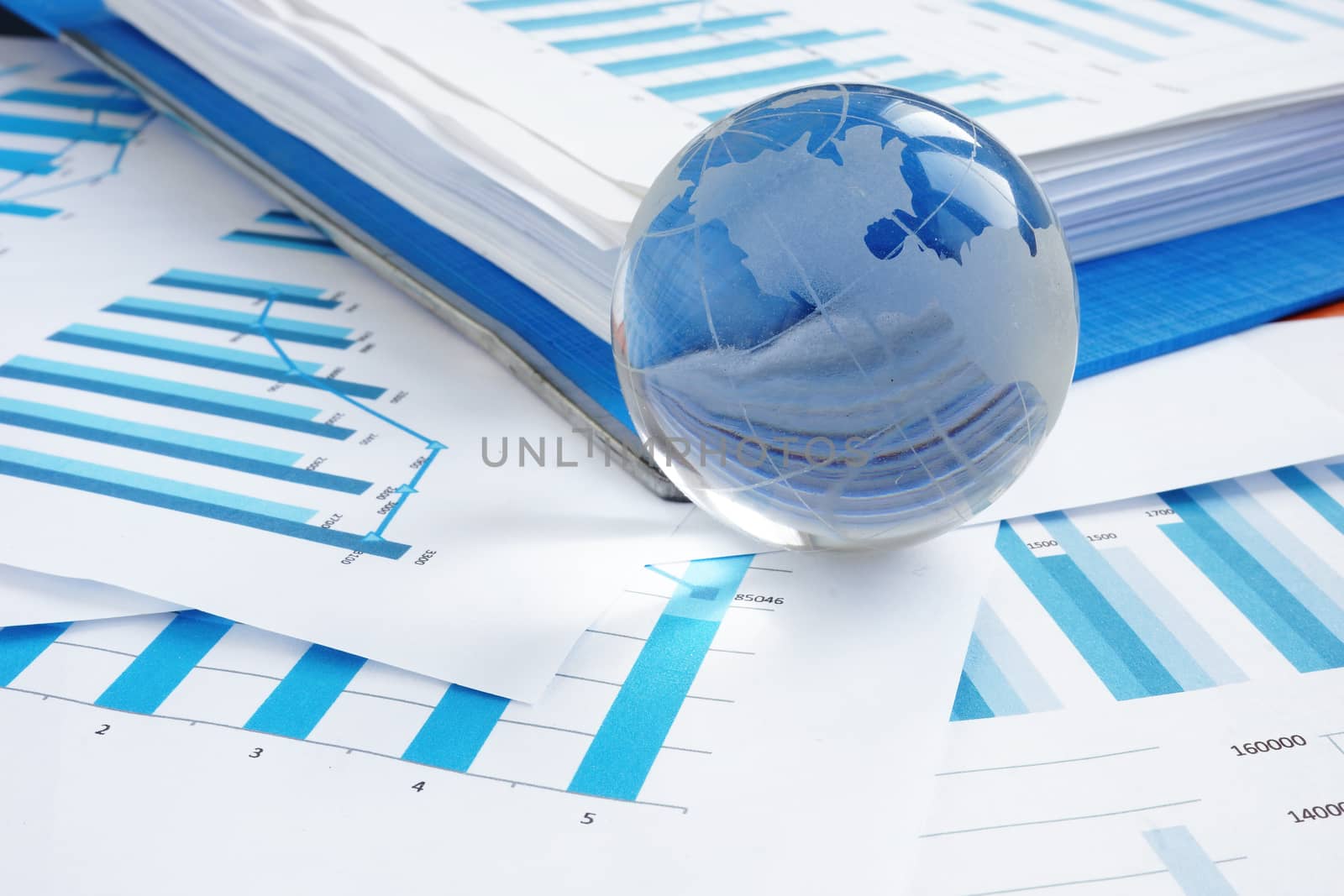 Global business concept. Glass globe and financial charts.